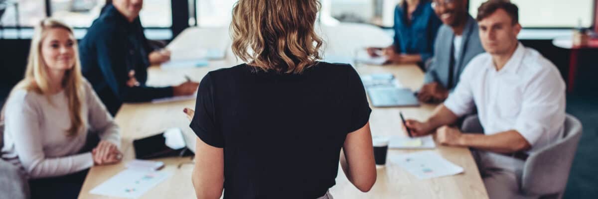 Rear view of a businesswoman addressing a meeting in office. Female manager having a meeting with her team in office boardroom.