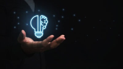Businessman holding virtual light bulb and half brain on blue bokeh background smart thinking concept and innovative ideas inspired