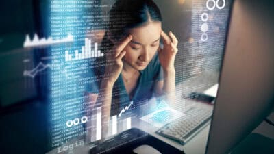 Shot of a young programmer looking stressed while using a computer at night in a modern office