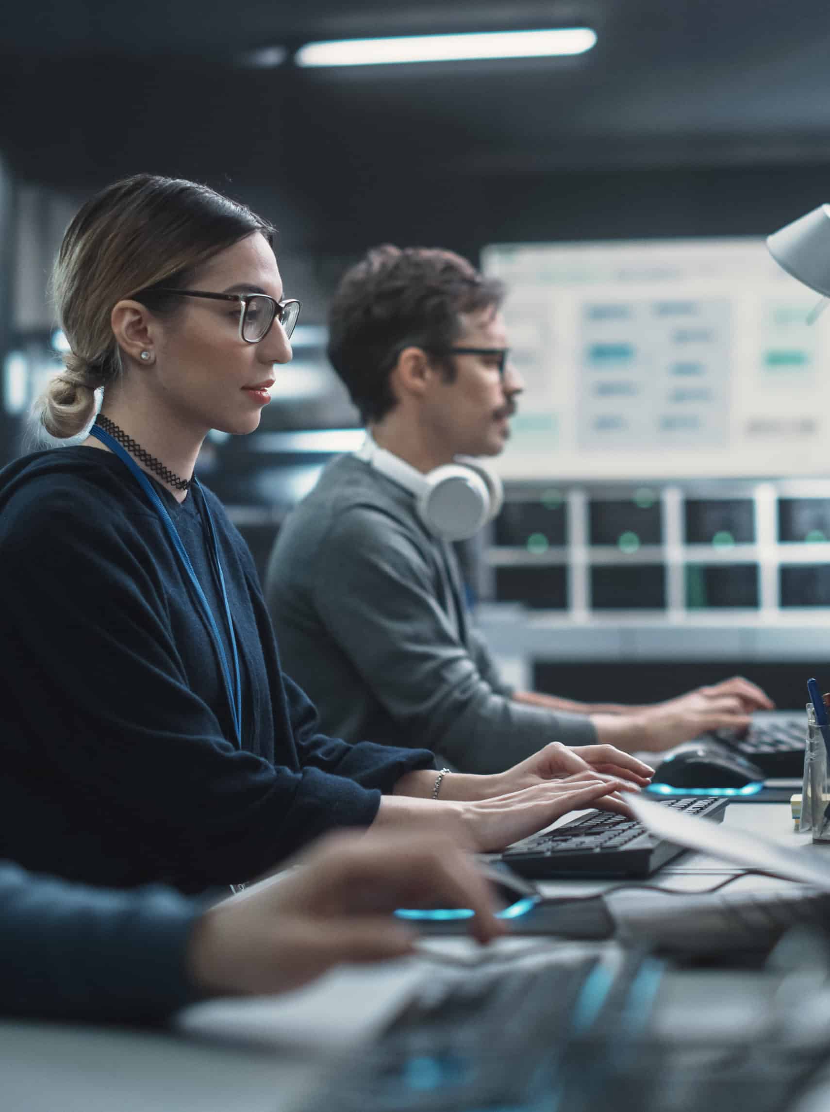 Focused Young Multiethnic Female Software Developer Working on Computer Together with Two Creative Male Colleagues. Data Protection Center with Servers, Storage Hardware and eBusiness Research